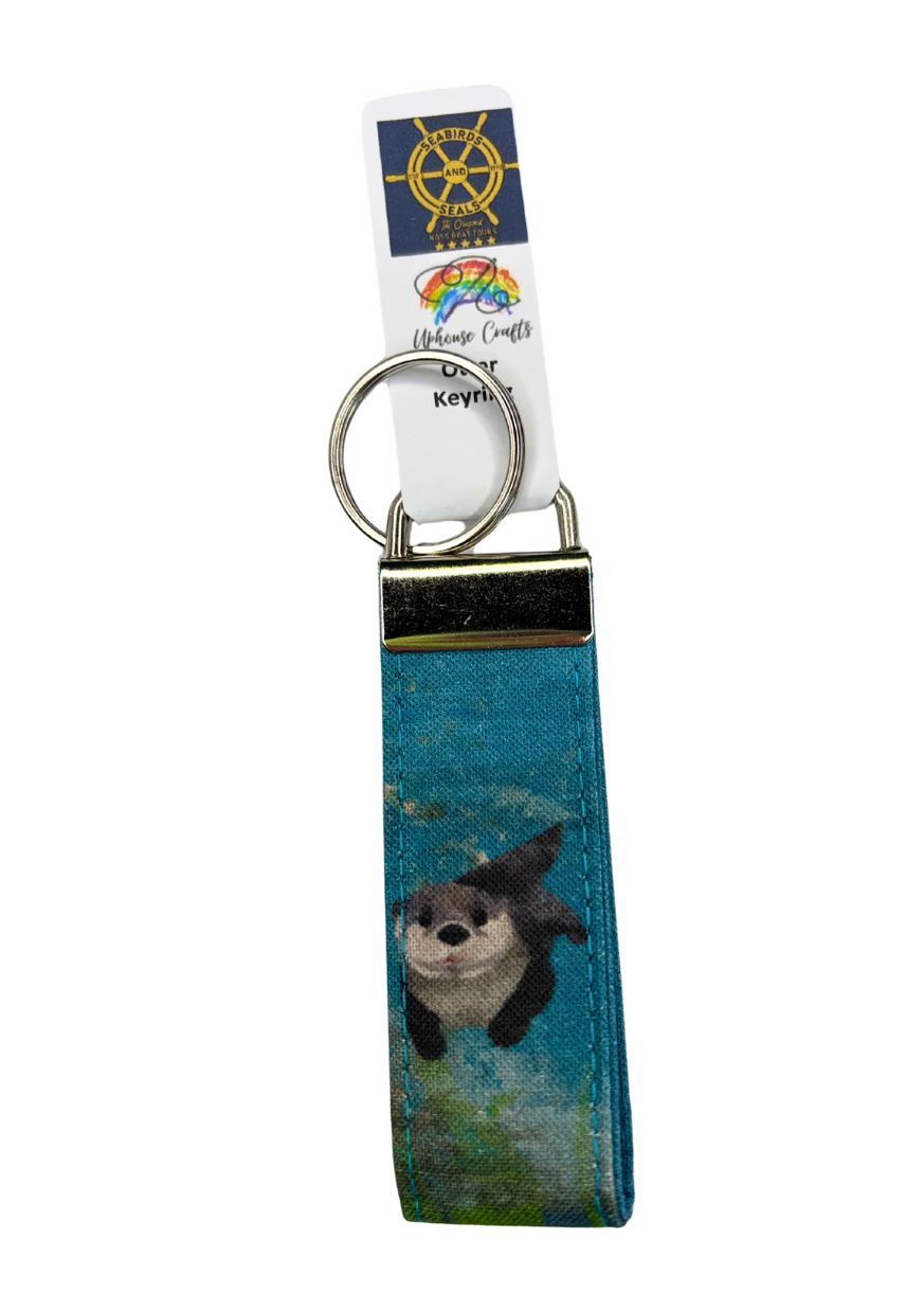 Keychain with a otter design on a blue background, featuring a tag with a rainbow symbol.